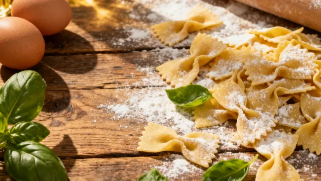 Fresh pasta, flour and basil on a wooden table